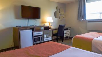 A hotel room with two beds, a desk with a computer, a television, and a microwave.