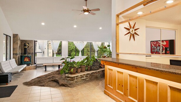 A modern living room with a fireplace, seating area, and a kitchen counter. - Howard Johnson by Wyndham Gravenhurst (Gravenhurst)