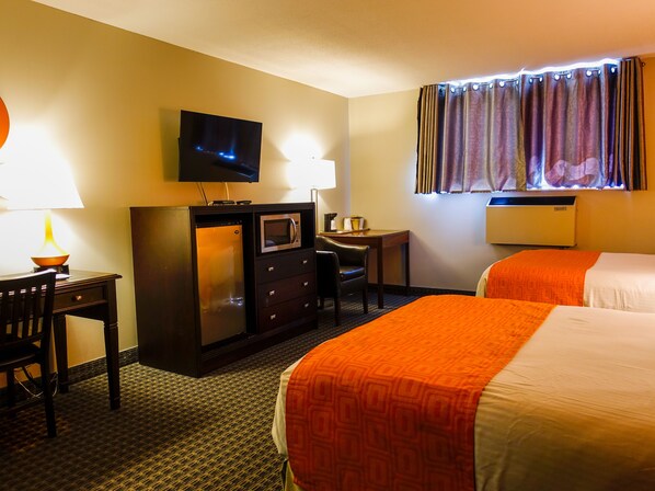 Habitación de hotel con dos camas, un escritorio, televisión, microondas y ventana con cortinas.
