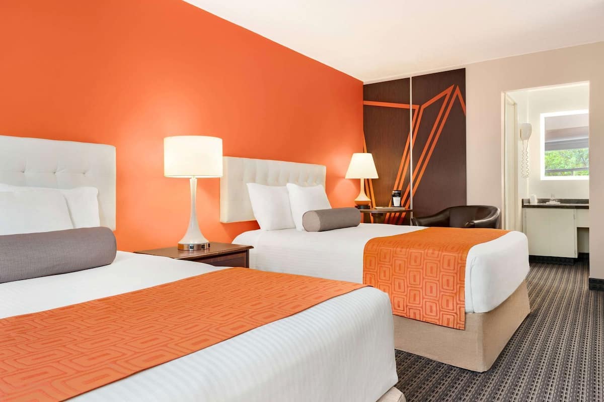 Una habitación de hotel con dos camas, zona de estar y baño.