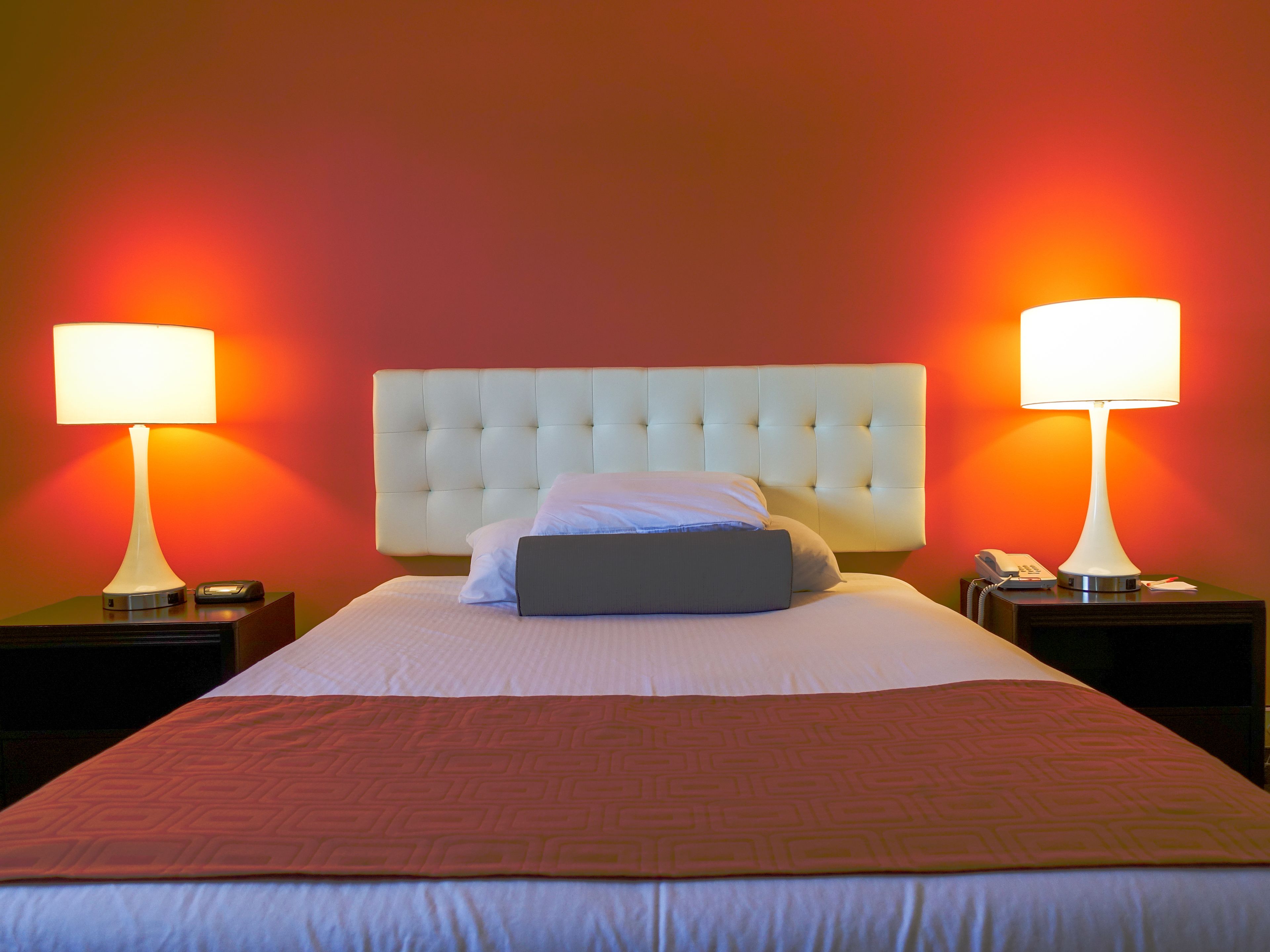 A hotel room with a large bed, two bedside lamps, a telephone, and a nightstand.