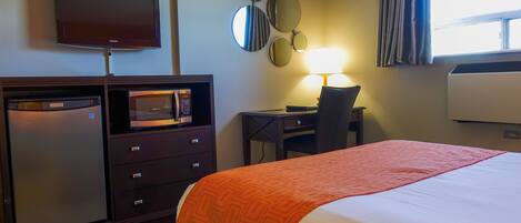 Une chambre d’hôtel équipée d’un lit, d’un bureau, d’un four à micro-ondes, d’une télévision et d’une lampe.