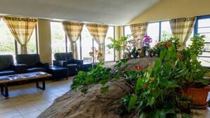 A spacious living room with a large rock centerpiece, comfortable seating, and large windows with curtains. - Howard Johnson by Wyndham Gravenhurst (Gravenhurst)