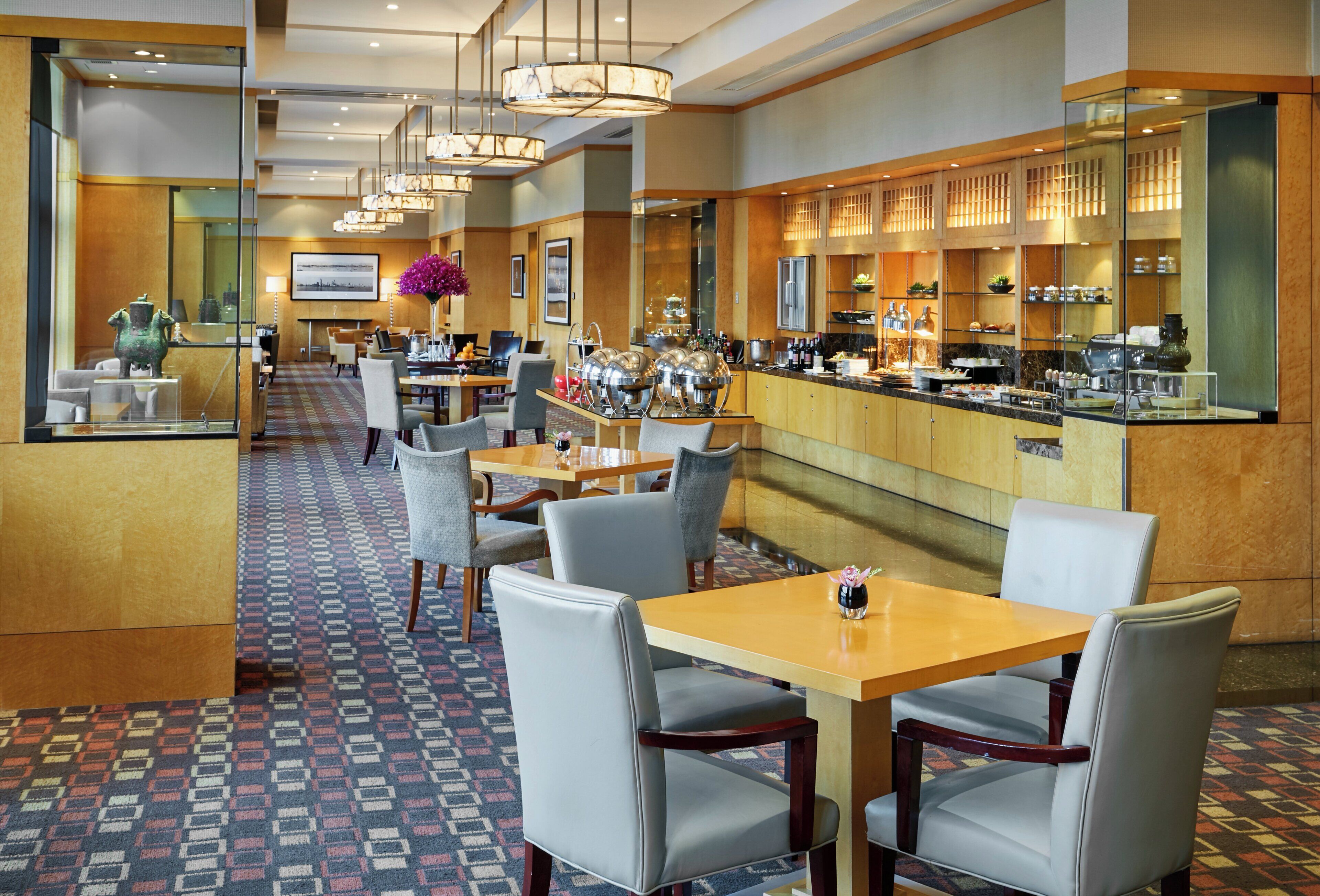 A hotel lobby with a bar area, seating arrangements, and a patterned carpet.