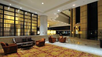A spacious lobby with a seating area, a large window with blinds, and a modern interior design.