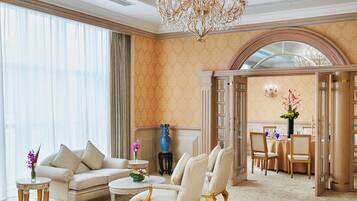 A luxurious living room with a chandelier, a sofa, chairs, and a dining area with a table and chairs.