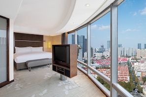 Habitació d'hotel moderna amb un llit gran, televisió de pantalla plana i vista a la ciutat.