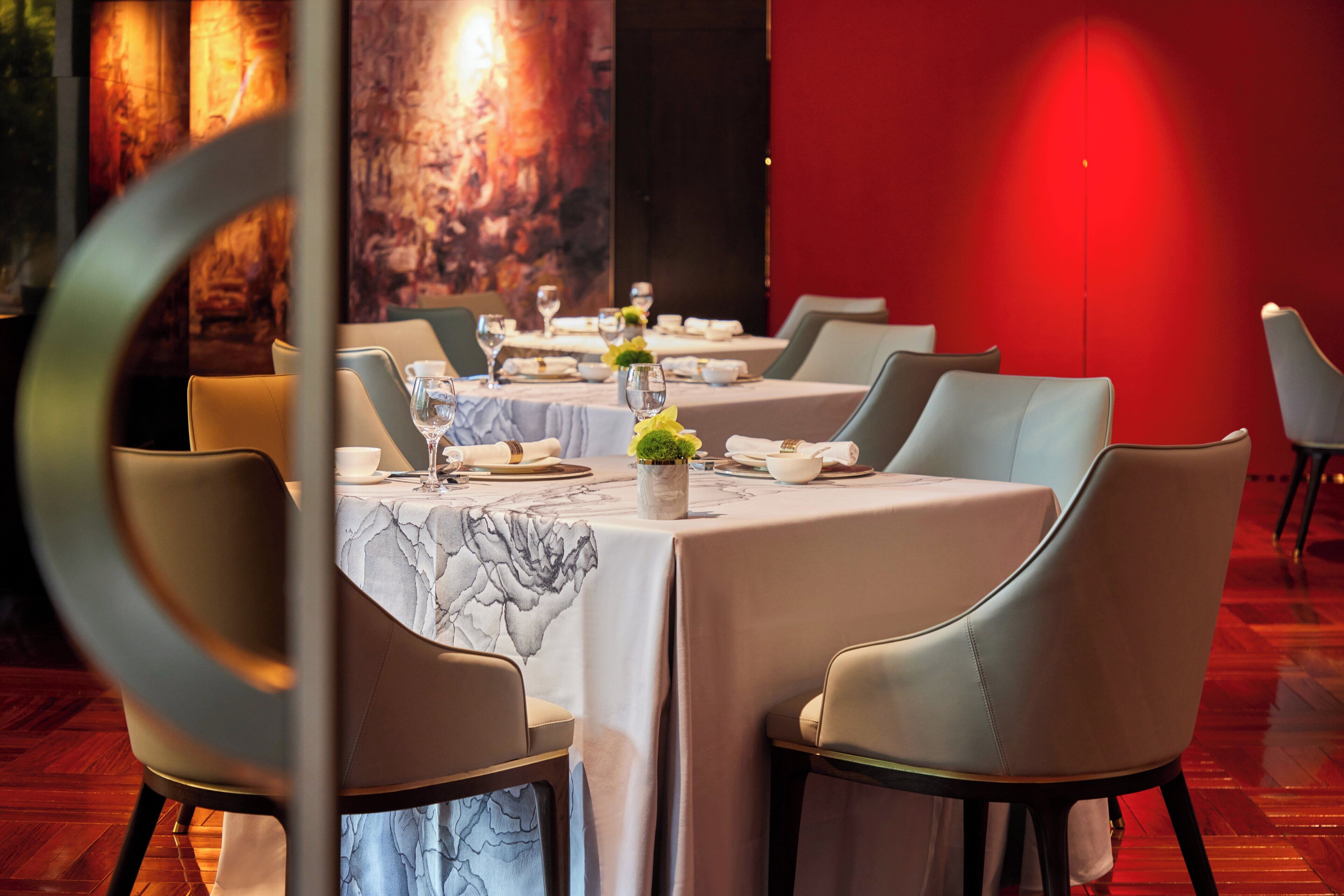 Un restaurante con mesas dispuestas para comer, con manteles de mármol y sillas verdes.