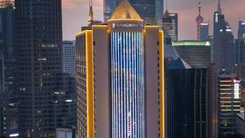A high-rise building with a distinctive vertical light pattern, surrounded by other skyscrapers and a busy street.