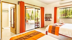 A hotel room with a bed, a TV, a small table, and a view of the outdoors.