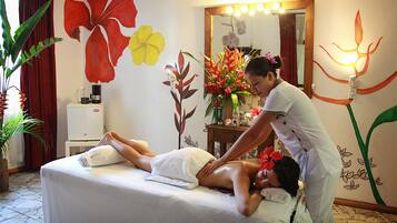 Relax in a serene space with a massage table, floral mural, and soothing ambiance.