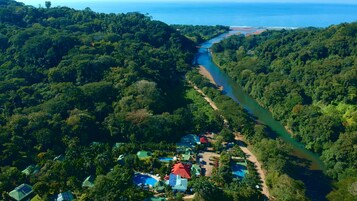 Vista aérea de un complejo turístico con un río que lo atraviesa, rodeado de un bosque denso.