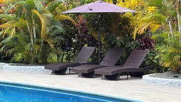A poolside area with lounge chairs and a canopy.