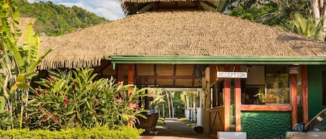 A reception area with a thatched roof and a sign indicating 'RECEPTION'.