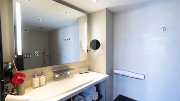 Une salle de bain moderne avec un grand miroir, un lavabo et une douche.