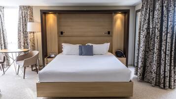 A hotel room with a large bed, a desk, and a chair.