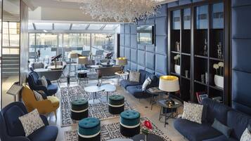 Un espacio lounge moderno con sofás, mesas y una amplia estantería.