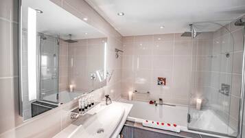 A modern bathroom with a large mirror, a bathtub, and a glass-enclosed shower.