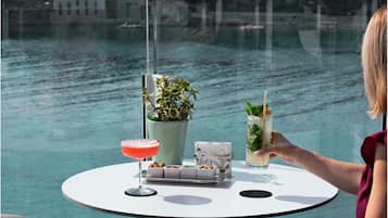 A table with a drink, a plant, and a tray of nuts.