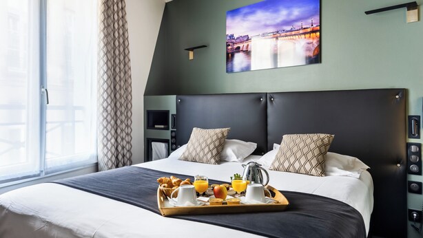 Et hotelværelse med en stor seng, et bakke med morgenmad og et bybillede på væggen.