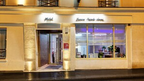 En hotelindgang med et skilt, der viser "Hotel" og "Louvre Sainte Anne".