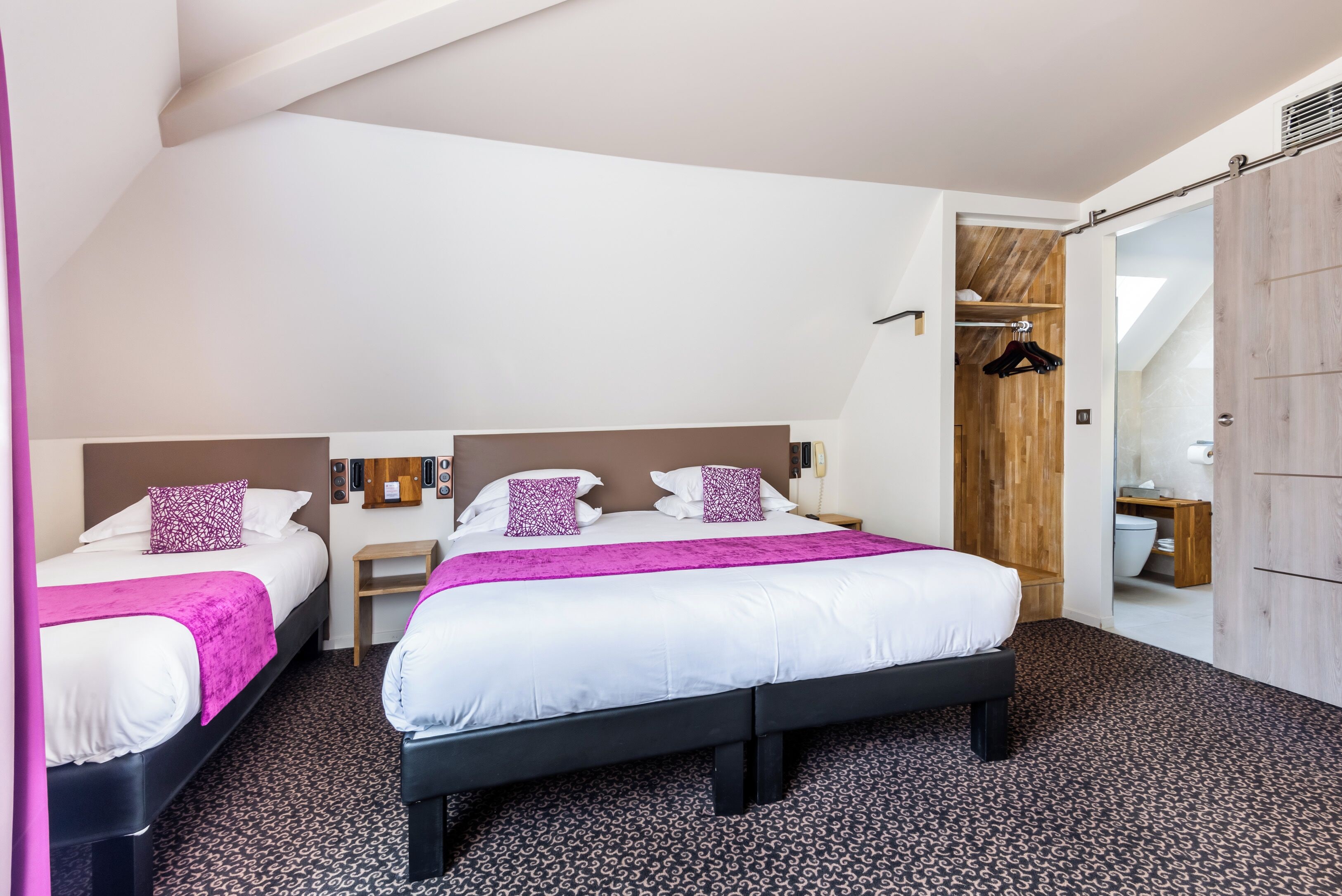 A modern hotel room with two beds, a large mirror, and a wooden wardrobe.