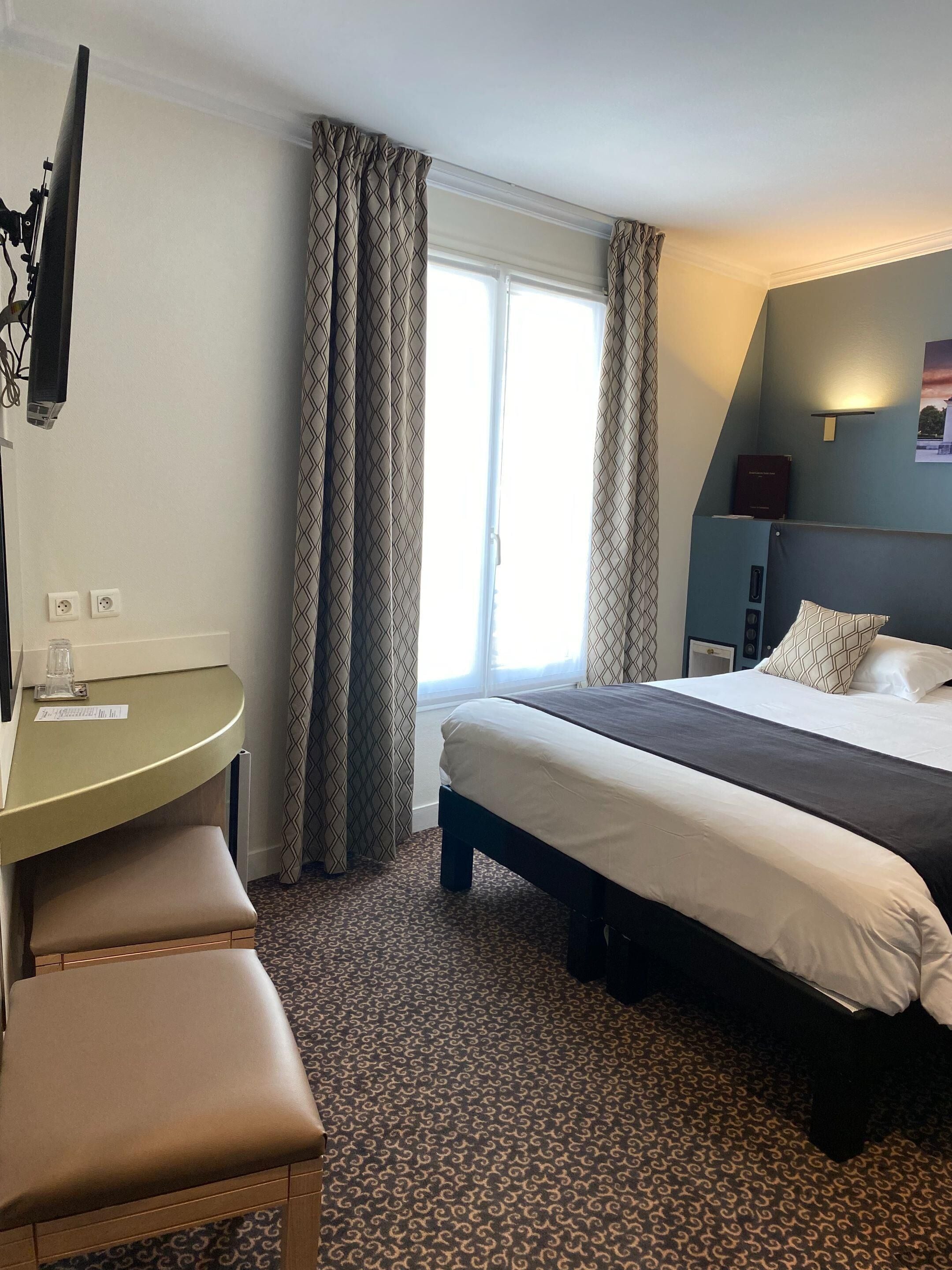 A hotel room with a bed, a desk, and a television.