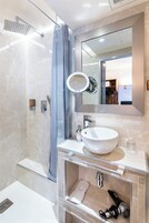 Un bagno moderno con box doccia in vetro, uno specchio grande, un lavandino bianco e un asciugacapelli integrato.