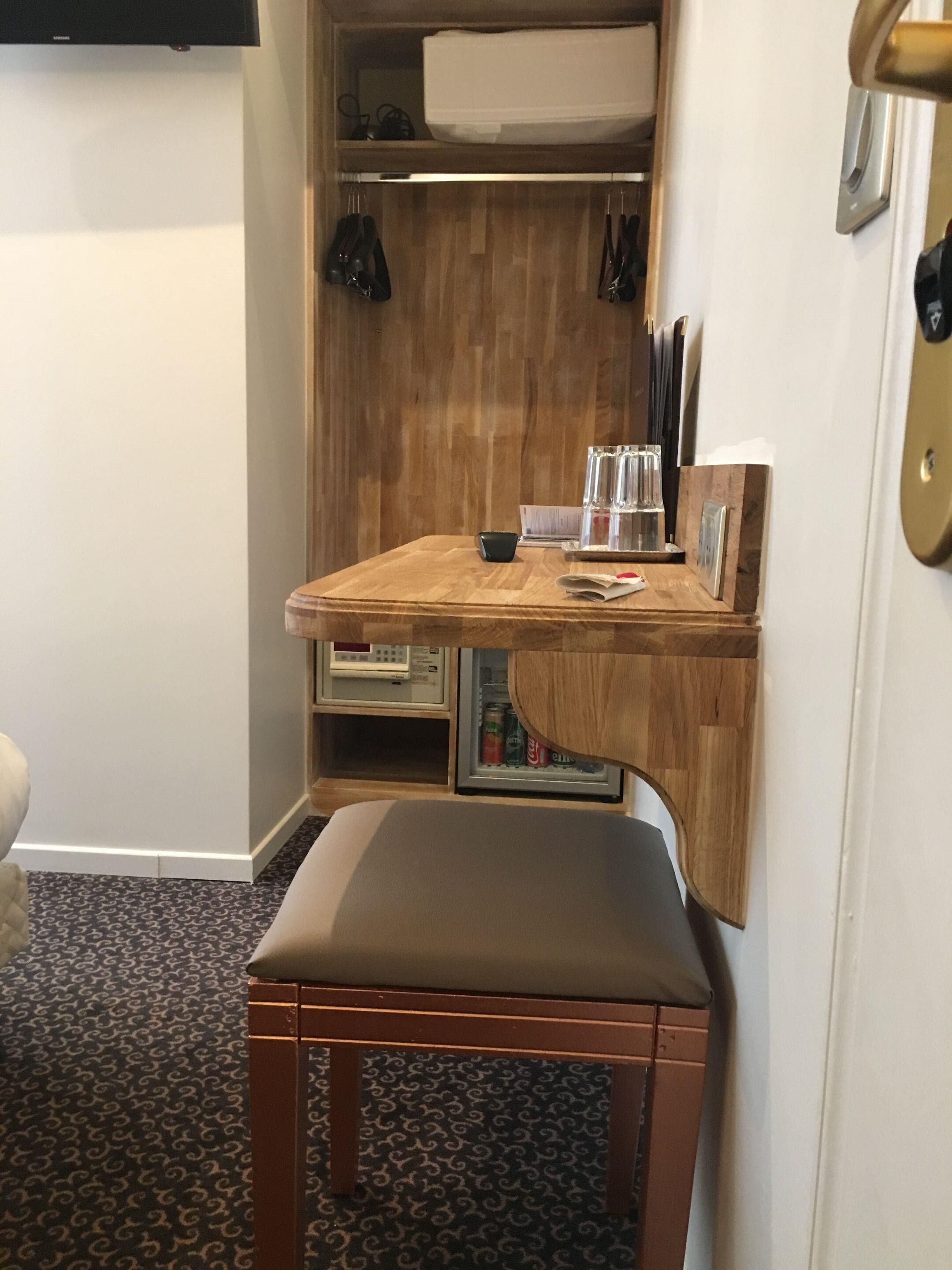 Eine kleine Küchenzeile mit Holzarbeitsplatte, einem Stuhl und einem Kühlschrank.