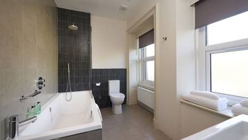 Une salle de bain moderne équipée d’une baignoire, de toilettes et d’une douche.