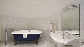 A bathroom with a freestanding bathtub, a sink, and a mirror.