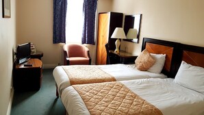 A hotel room with two beds, a desk with a lamp, a chair, and a television. - The Ashley Hotel (Altrincham)