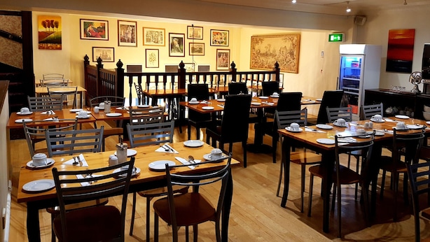A restaurant with multiple tables and chairs, a buffet area, and a refrigerator. - The Ashley Hotel (Altrincham)