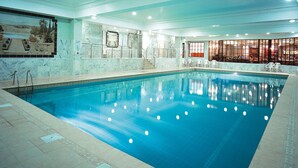 An indoor swimming pool with clear water, tiled walls, and a seating area with chairs. - Royal Court Hotel (Coventry)