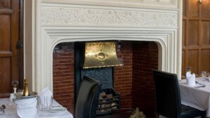 A dining area with a fireplace, a table set for two, and a patterned carpet. - Royal Court Hotel (Coventry)