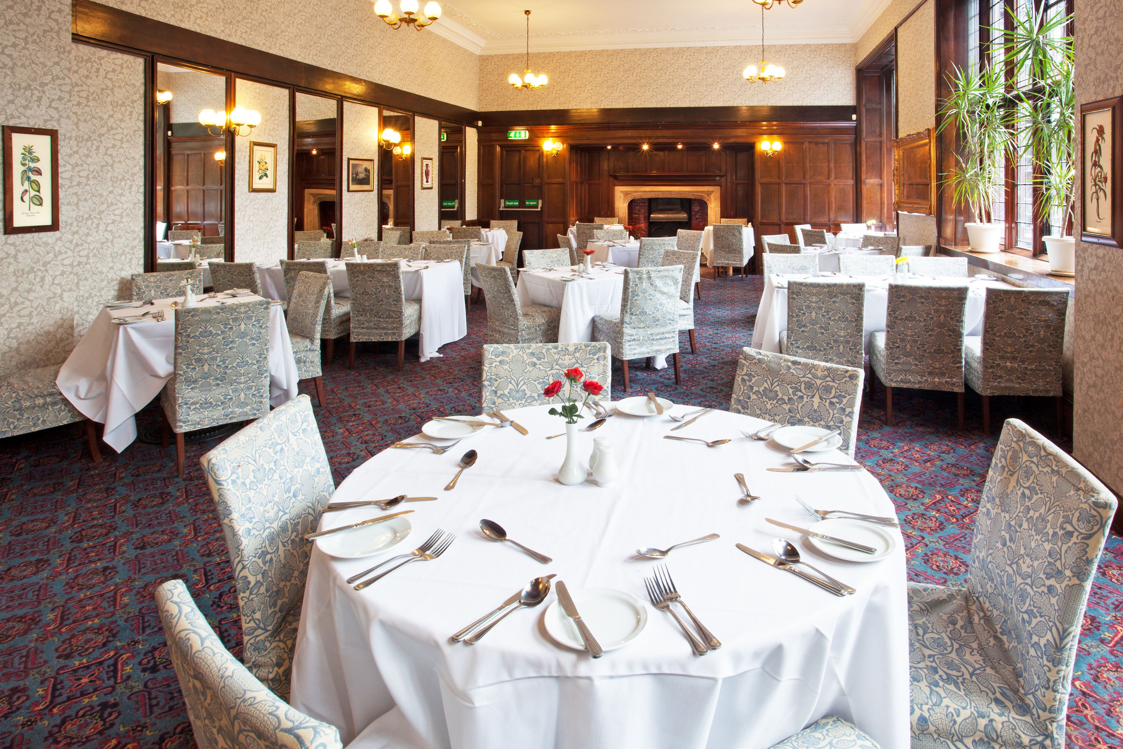 A banquet hall with round tables set for a formal event, featuring white tablecloths and silverware.