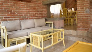 Un salon avec un mur en briques, un canapé, une table basse et un coin repas comprenant des chaises et une table.