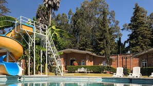 Une piscine avec un toboggan et un bâtiment en briques en arrière-plan.