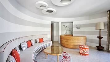 A modern living room with a curved sofa, a round coffee table, and a unique wall-mounted lamp.