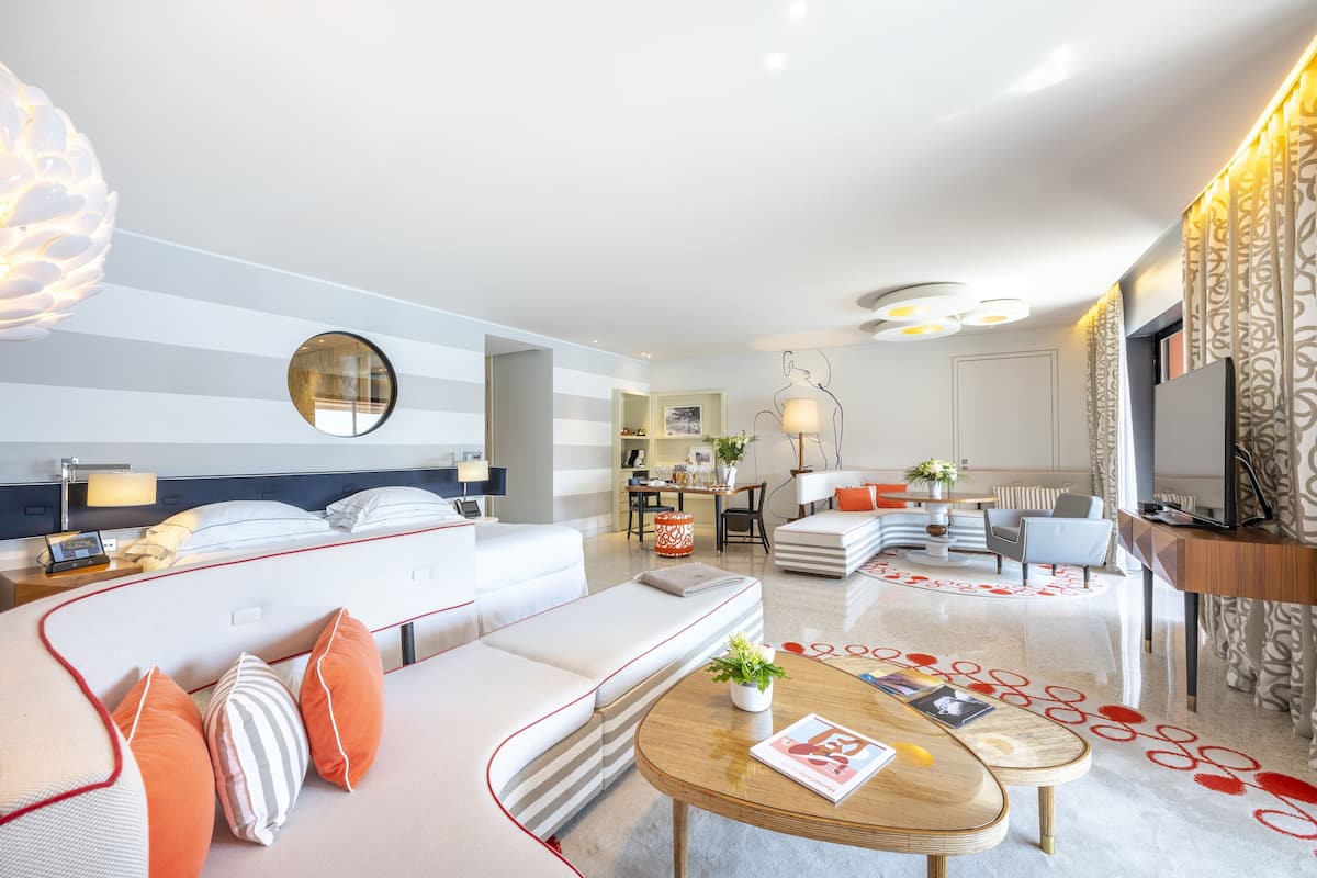 Une chambre d’hôtel moderne équipée d’un canapé, d’une table basse ronde, d’un téléviseur et d’un coin repas avec une table et des chaises.