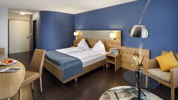 Ein Hotelzimmer mit einem Bett, einem Schreibtisch mit Stuhl, einer Couch und einem runden Tisch.