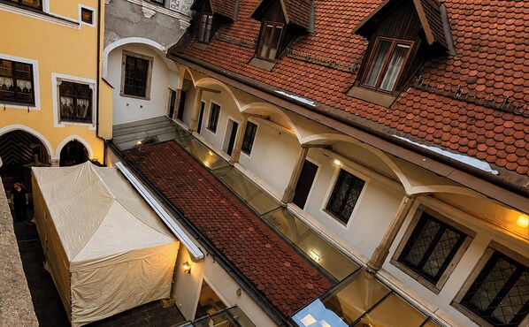 A multi-story building with a covered outdoor area, multiple windows, and a tiled roof.