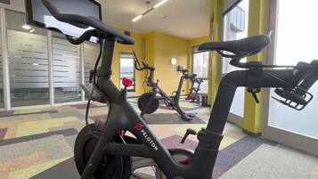 Ein Fitnessraum mit Ergometer, Laufband und einer Gewichtshalterung.