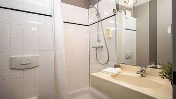 A modern bathroom with a glass shower enclosure, a white toilet, a sink with a mirror, and a towel on the counter.
