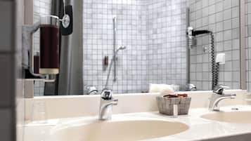 Un baño con dos lavamanos, un espejo, un perchero para toallas y una ducha.