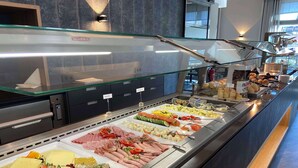 Un bufé con diversas opciones de comida, como carnes, quesos y frutas.