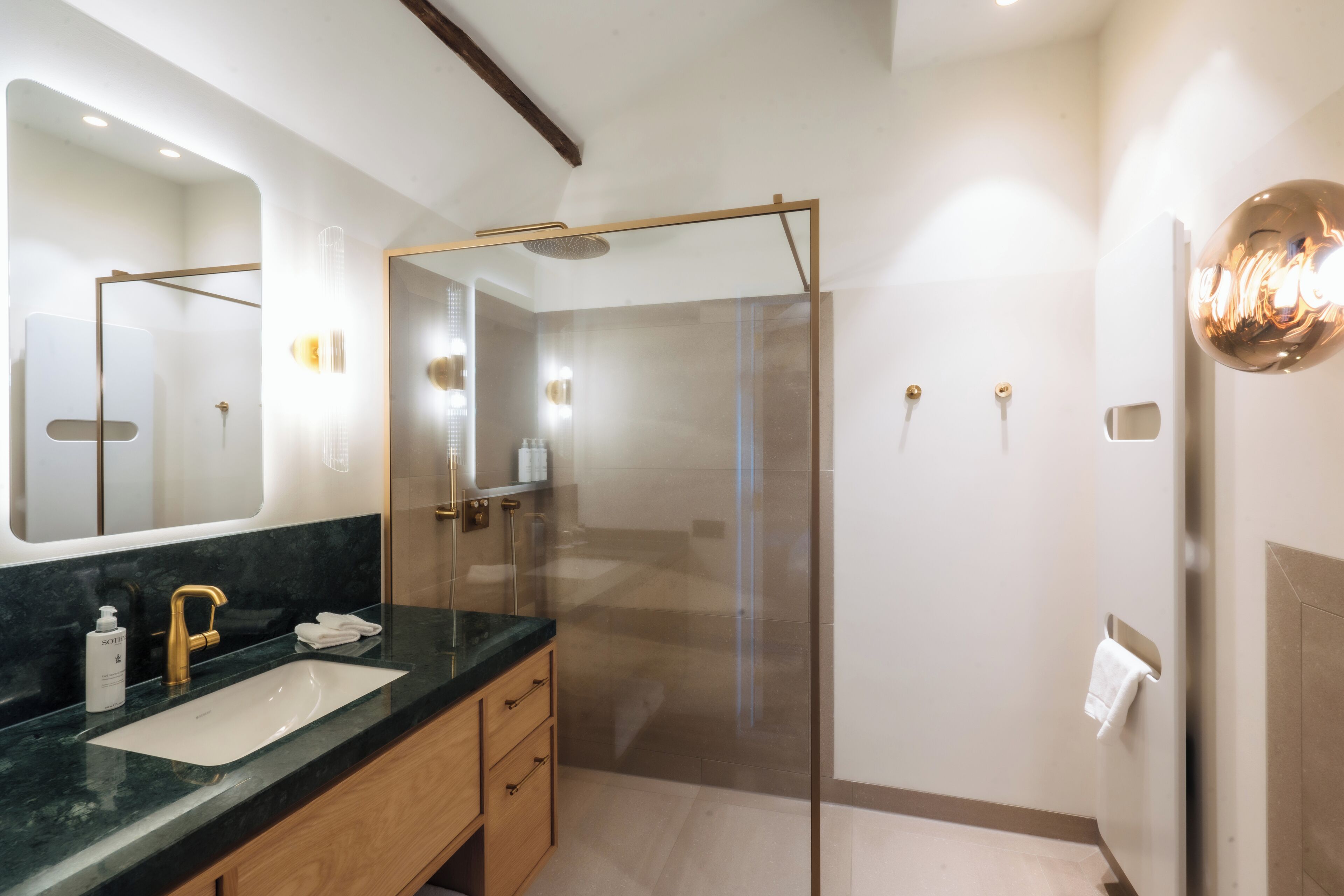Een moderne badkamer met een douchecabine van glas, een marmeren wastafel en een grote spiegel.