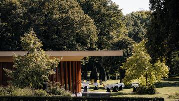 A modern building with a covered outdoor area, surrounded by trees and well-maintained grass.