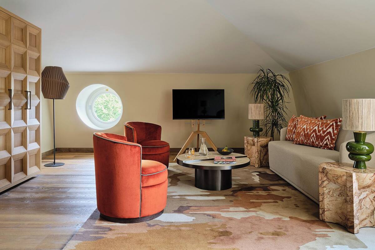 Un salon moderne avec une fenêtre ronde, un téléviseur, un canapé et une table basse.