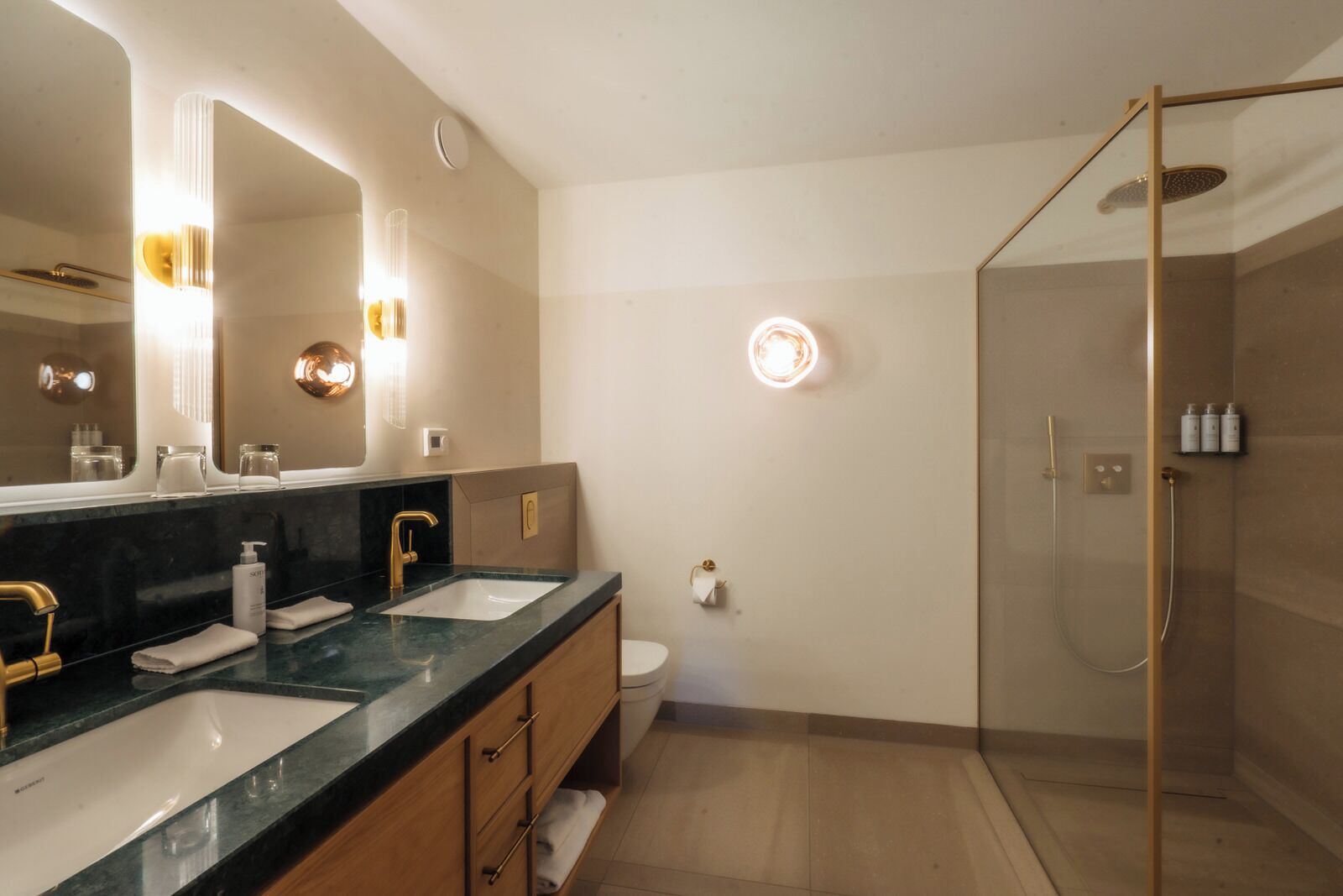 Un baño moderno con dos lavamanos, un espejo grande y cabina de ducha con paredes de vidrio.